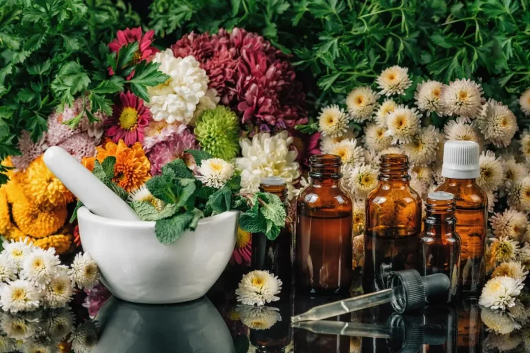 Mortier avec des herbes Mortier avec des herbes, flacons en verre et fleurs colorées en arrière-plan.